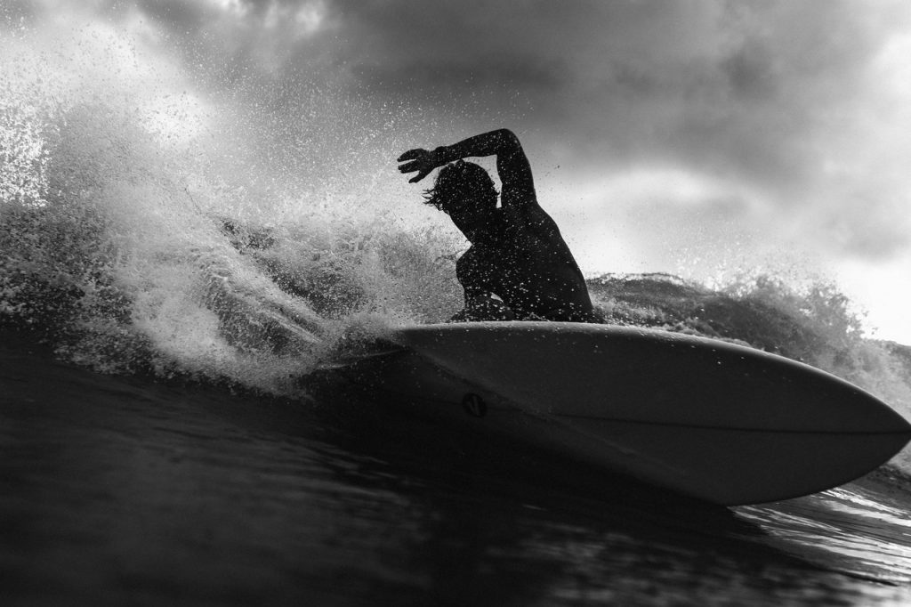 Silhouette of unrecognizable surfer on board