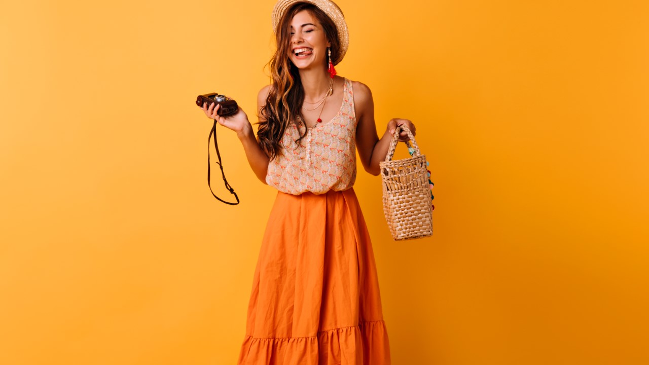 Blissful lady in trendy summer clothes posing with camera on yel