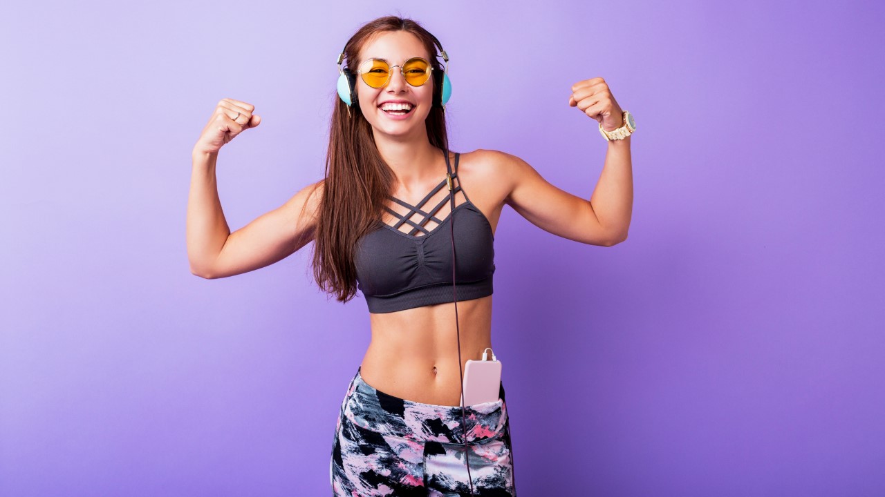 Exited sporty woman demonstrate muscule in studio.